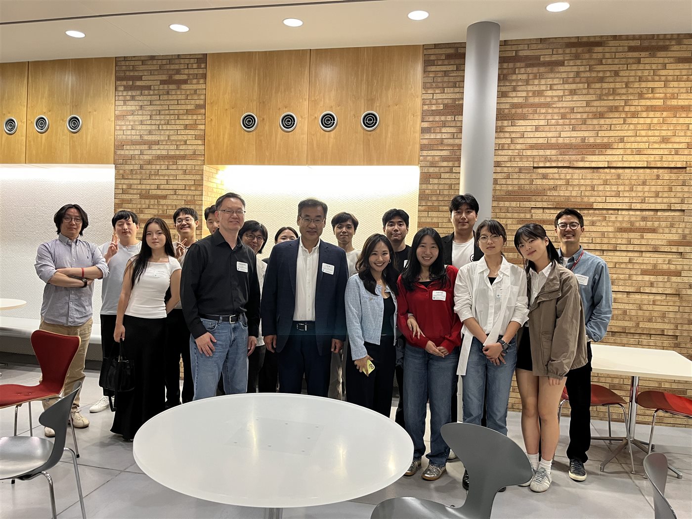 Around sixteen attendees standing together for a group photo in a brick-walled atrium at Cornell