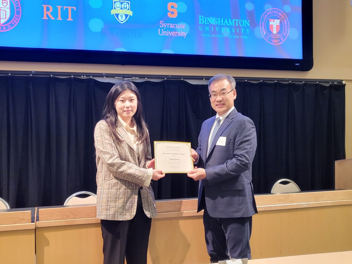 A student receiving a Best Presentation Award certificate on stage