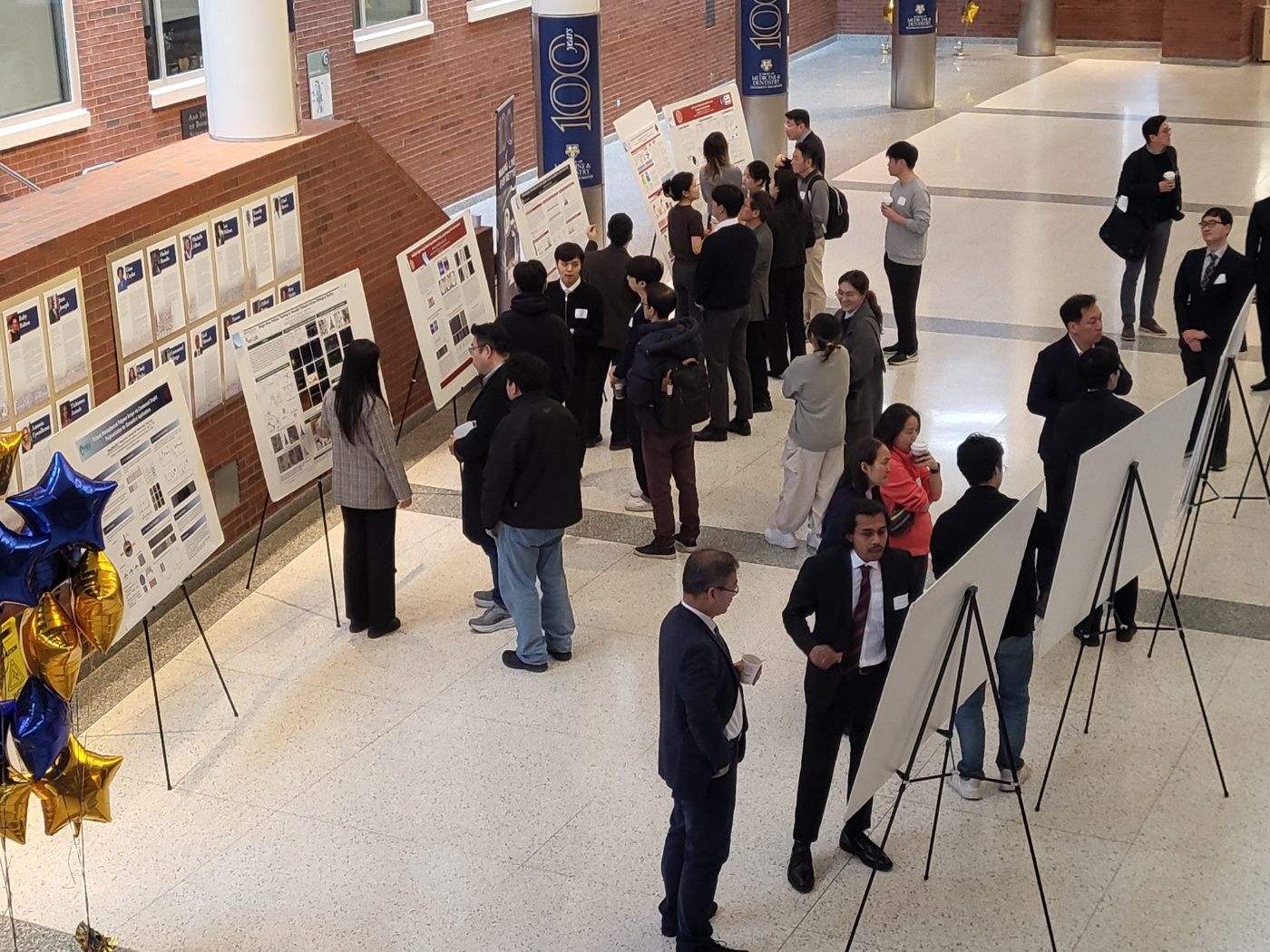 Students standing beside their posters discussing their research with faculty visitors