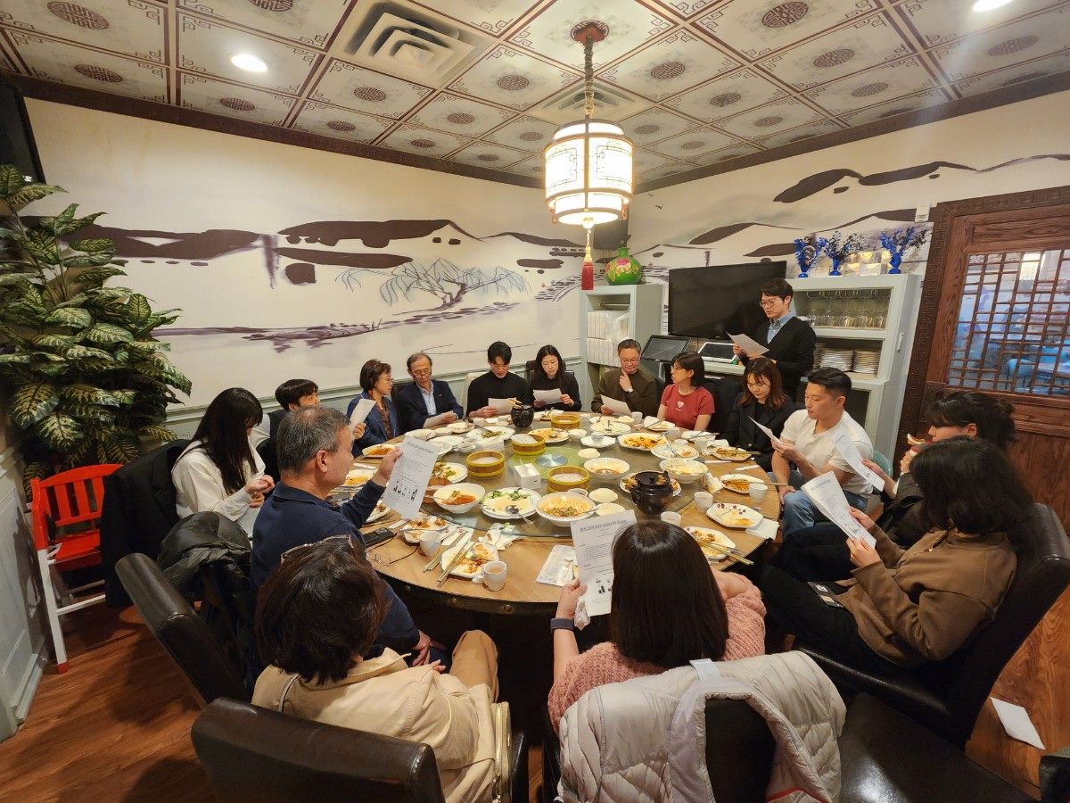 Chapter members seated around a large round table at a restaurant, reading printed agenda documents